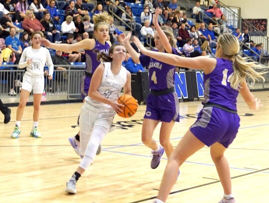 Reagan Greenroyd, a freshman, draws the triple team when taking it to the hoop in the Newcastle-Chickasha game last week. Senior Natalie Orr watches the play develop. • photo by Jennifer Lewis