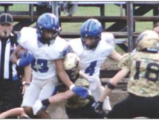 Jordan Lane runs the ball with a Woodward Boomer on his heels. Rex Heskew waits to aid his Racer teammate. • by Lisa Smith-Longman