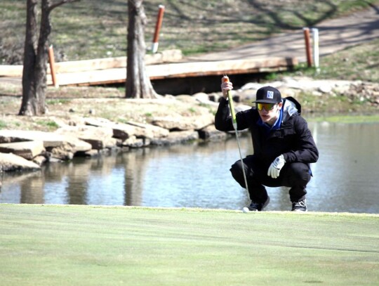 Colton Bradley looks for the line while preparing to putt for the Racer Golf team. • photo by Valerie Hobbs