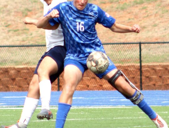 • photo by Mindi Stucks Gage Bell keeps his opponent away from the ball during recent Racer soccer.